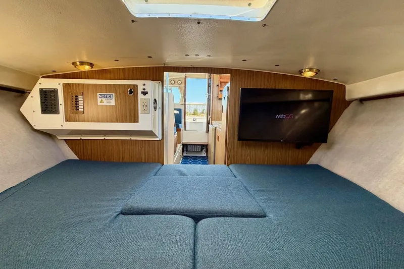 Slide: The Image of Interior of 1981 Bertram 28 Flybridge Cruiser with blue seating and wall-mounted TV. - 24