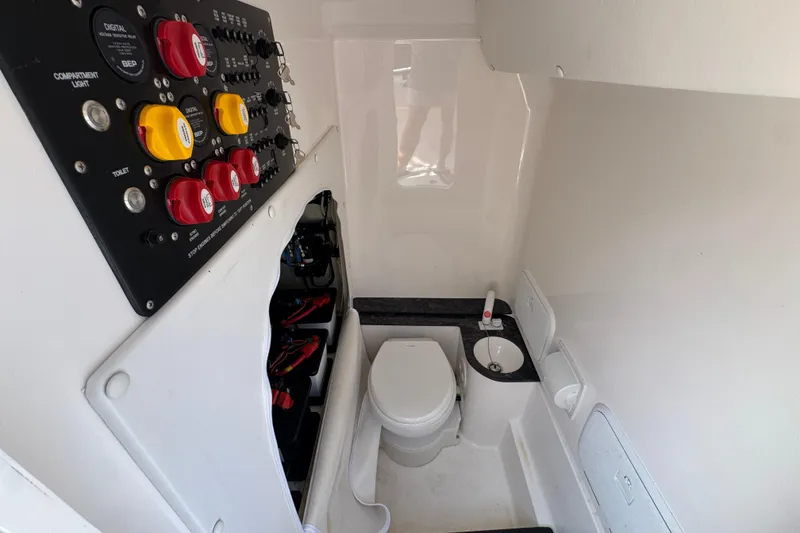 Slide: The Image of 2024 Fountain Bluewater 38 Tournament Edition boat interior with control panel and compact bathroom. - 22
