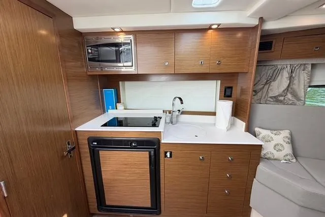 Slide: The Image of 2016 Cruisers Yachts 390 Express Coupe kitchen with wood cabinetry and modern appliances. - 17