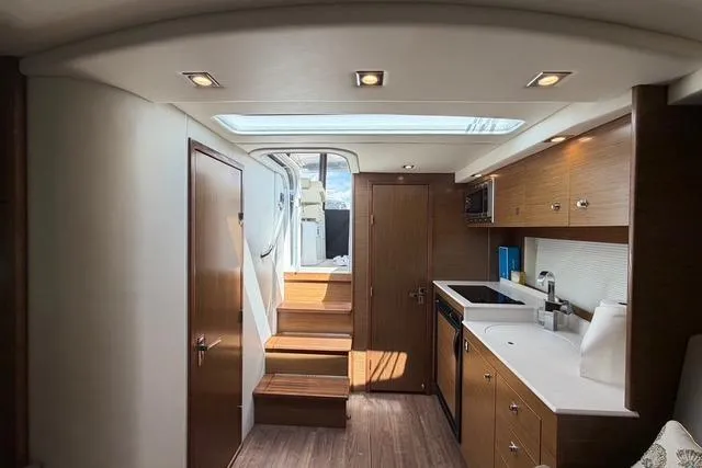 Slide: The Image of Interior of 2016 Cruisers Yachts 390 Express Coupe, featuring modern kitchen and wooden cabinetry. - 20