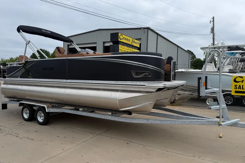 The Image of 2026 Avalon LSZ Rear Fish pontoon boat on trailer, parked outside dealership. - 0