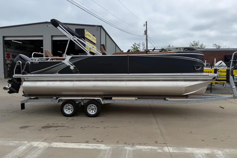 Slide: The Image of 2026 Avalon LSZ Rear Fish pontoon boat on trailer, parked outside a garage. - 2