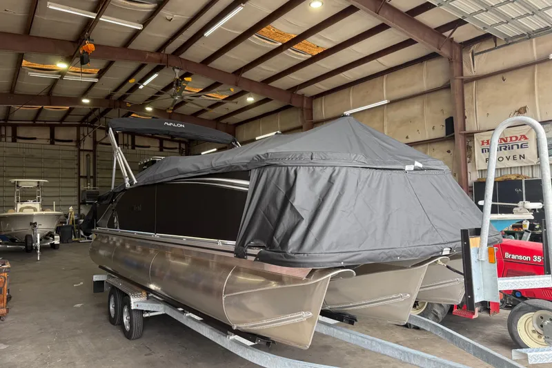 Slide: The Image of 2026 Avalon LSZ Rear Fish pontoon boat covered in a garage setting. - 30