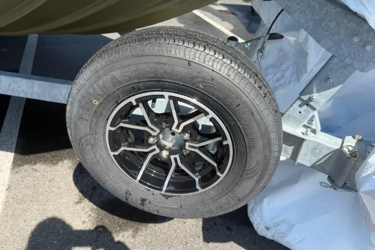 Slide: The Image of Trailer wheel of 2026 Crestliner 1870 Retriever FCC boat, featuring black alloy rim. - 2