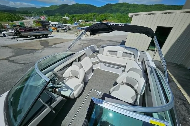 Slide: The Image of 2019 Four Winns HD220 boat with spacious seating, parked outdoors near scenic mountains. - 11