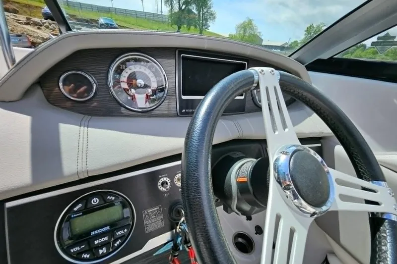 Slide: The Image of Steering wheel and dashboard of 2019 Four Winns HD220 boat, featuring gauges and controls. - 16