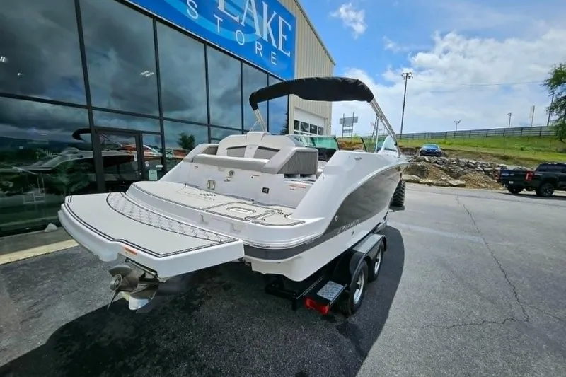 Slide: The Image of 2019 Four Winns HD220 boat on trailer outside a showroom under a partly cloudy sky. - 2
