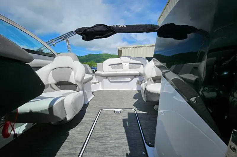 Slide: The Image of 2019 Four Winns HD220 boat interior with seating and open deck under blue sky. - 8