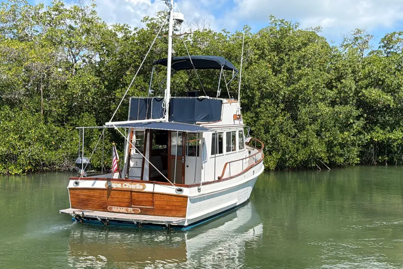 Slide: The Image of 1983 Grand Banks 32 Sedan boat cruising on a calm river with lush greenery. - 10
