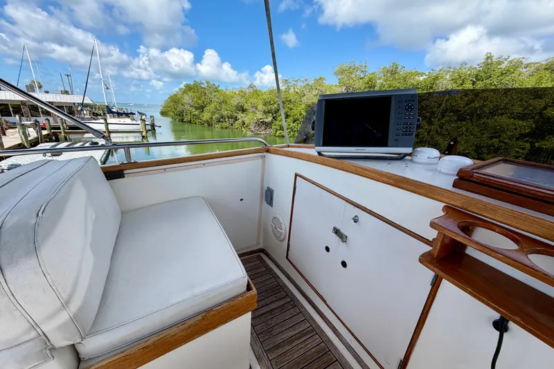 Slide: The Image of 1983 Grand Banks 32 Sedan boat interior with navigation equipment, docked near lush greenery. - 15
