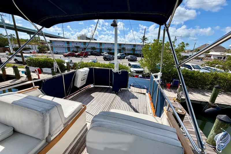 Slide: The Image of 1983 Grand Banks 32 Sedan yacht docked, featuring spacious deck and seating under blue canopy. - 16