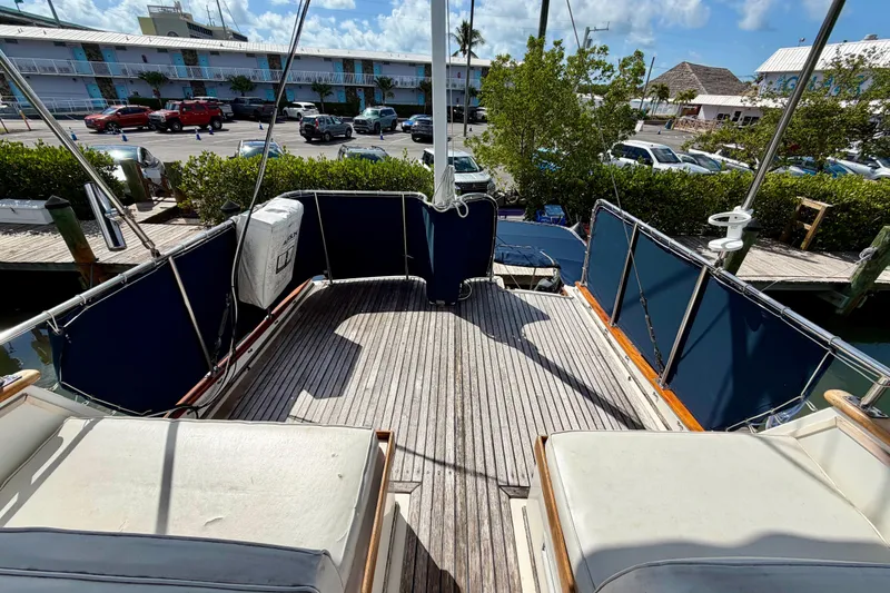 Slide: The Image of 1983 Grand Banks 32 Sedan boat deck with blue canvas, docked near parked cars. - 17