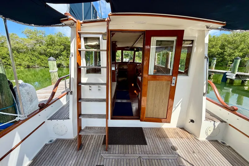 Slide: The Image of 1983 Grand Banks 32 Sedan boat interior with wooden door and steps, docked by lush greenery. - 21