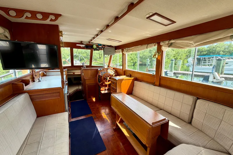 Slide: The Image of Interior of a 1983 Grand Banks 32 Sedan boat with wooden furnishings and large windows. - 3