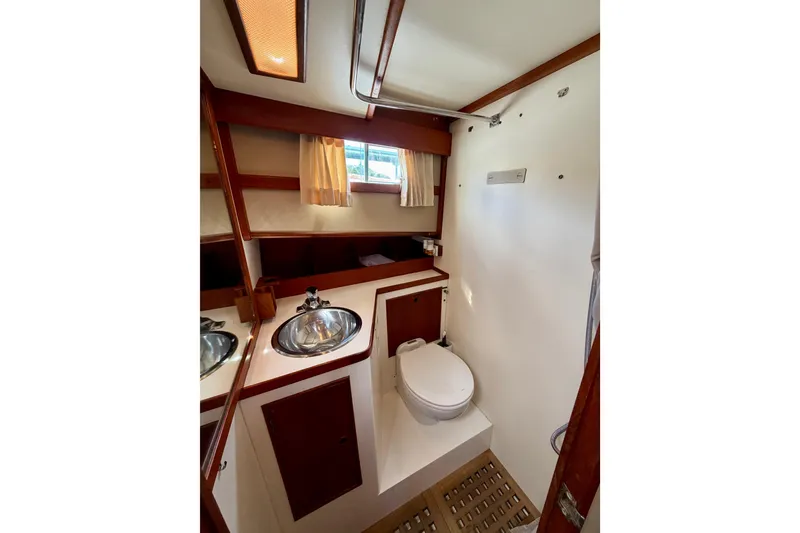 Slide: The Image of 1983 Grand Banks 32 Sedan bathroom with sink, toilet, and wooden accents. - 44