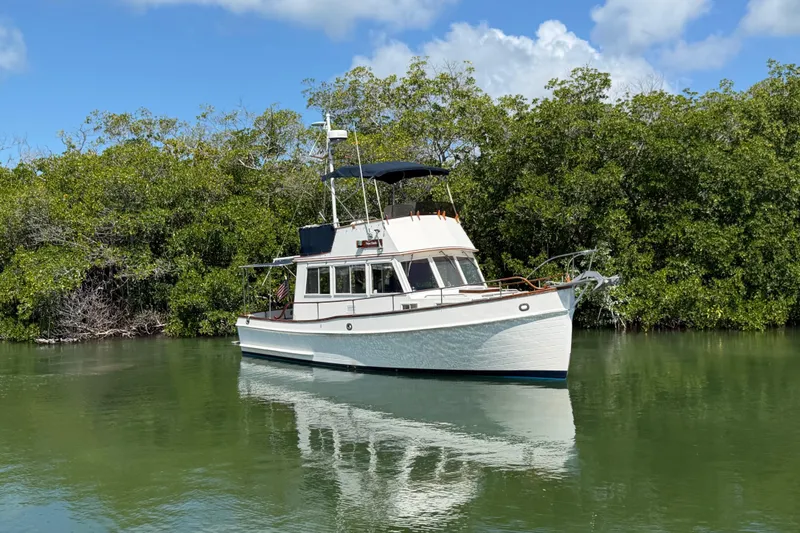 Slide: The Image of 1983 Grand Banks 32 Sedan boat on calm water, surrounded by lush greenery. - 6
