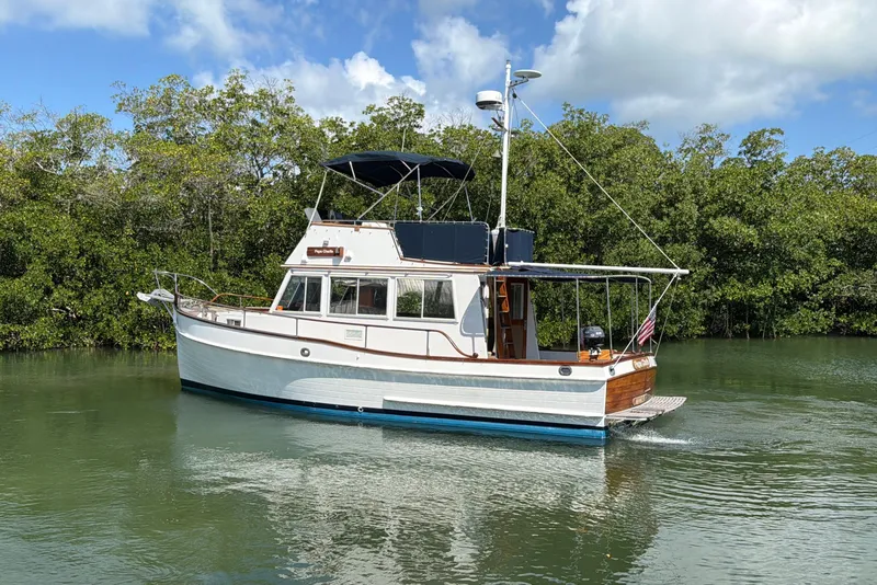 Slide: The Image of 1983 Grand Banks 32 Sedan cruising on a calm river with lush greenery. - 8