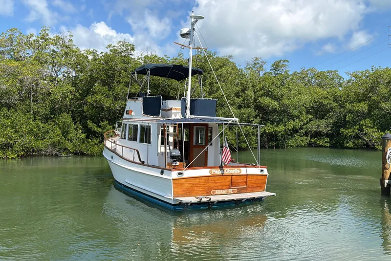 Slide: The Image of 1983 Grand Banks 32 Sedan boat on calm water, surrounded by lush greenery. - 9
