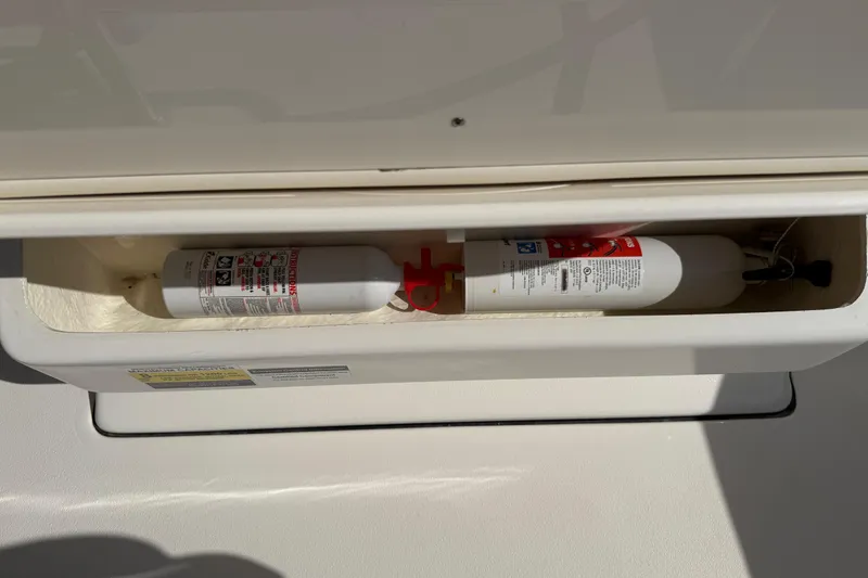 Slide: The Image of Fire extinguishers stored in a compartment on a 2017 Key West 219 FS boat. - 32