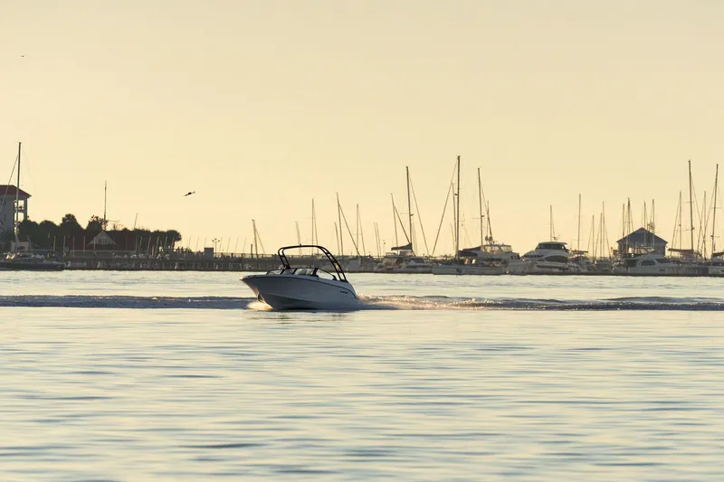 Slide: The Image of Stingray 20 SBX 2026 boat cruising on calm water at sunset. - 13