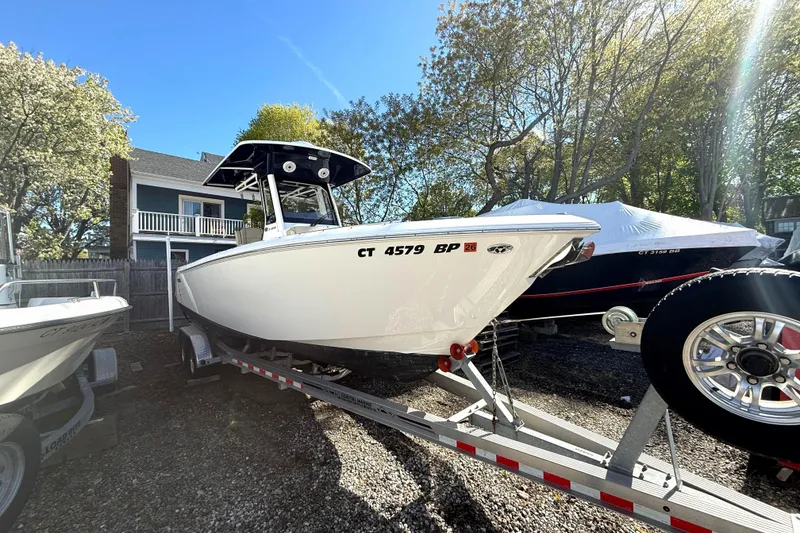 The Image of 2021 Pursuit S 268 Sport boat on trailer, parked outdoors under clear sky. - 0