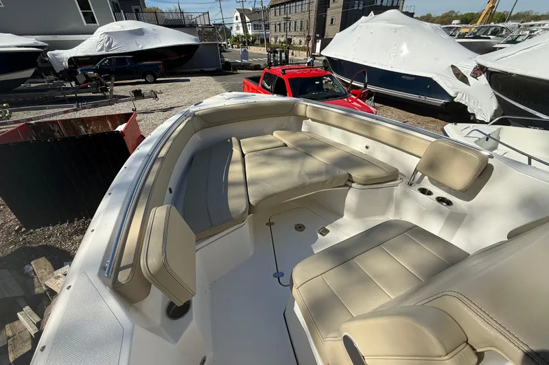 Slide: The Image of 2021 Pursuit S 268 Sport boat interior with beige seating in a marina setting. - 13
