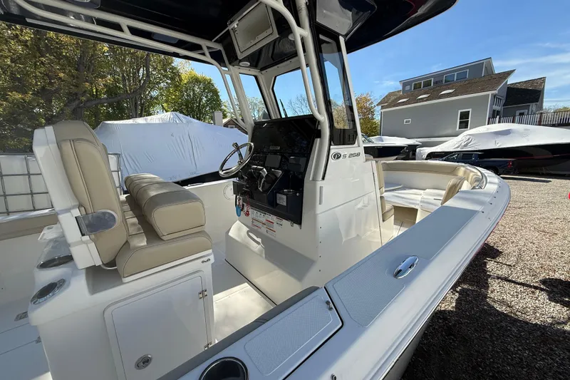 Slide: The Image of 2021 Pursuit S 268 Sport boat interior with helm and seating, parked outdoors. - 8