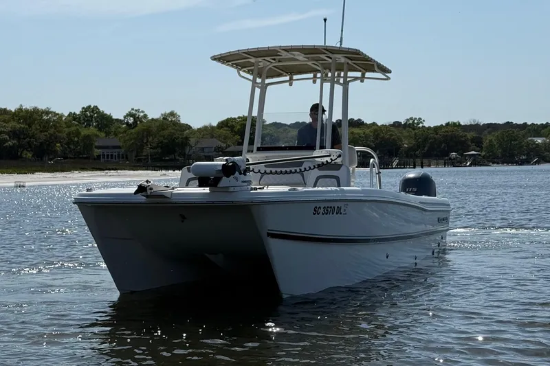 Slide: The Image of 2019 World Cat 230 CC boat cruising on a calm lake with scenic background. - 10