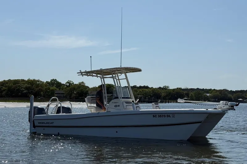 Slide: The Image of 2019 World Cat 230 CC boat on calm water, side view with trees in background. - 11