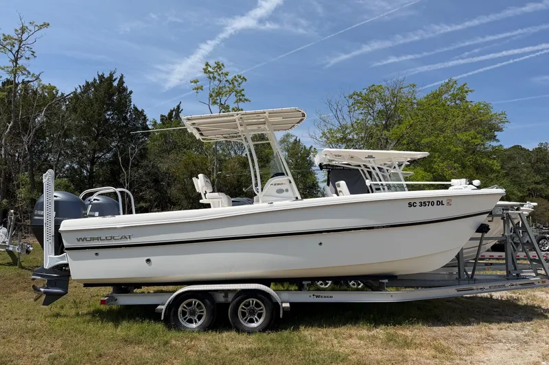Slide: The Image of 2019 World Cat 230 CC boat on trailer, parked outdoors with trees in background. - 2