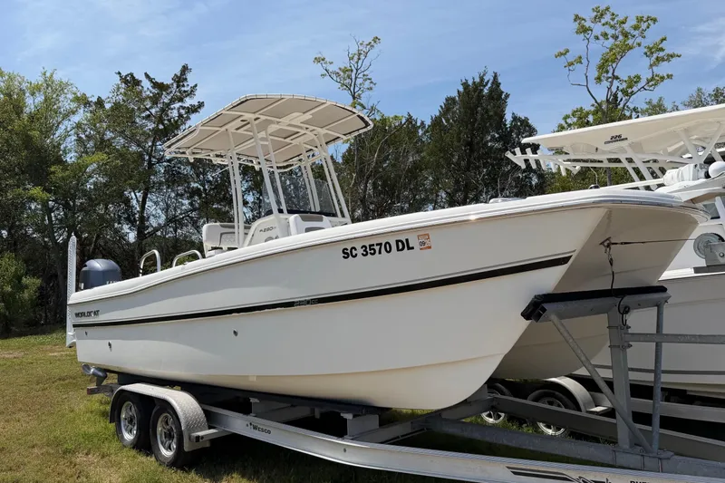Slide: The Image of 2019 World Cat 230 CC boat on trailer, parked outdoors with trees in background. - 3