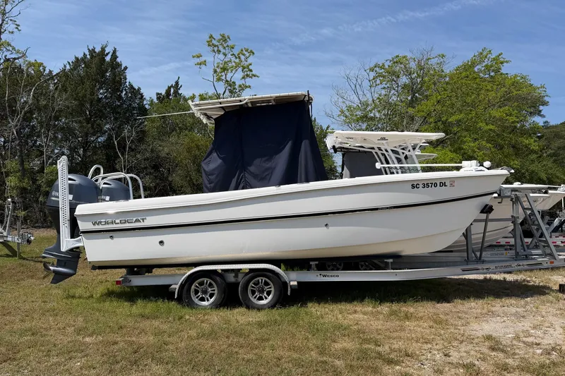 Slide: The Image of 2019 World Cat 230 CC boat on trailer, parked on grass with trees in background. - 31
