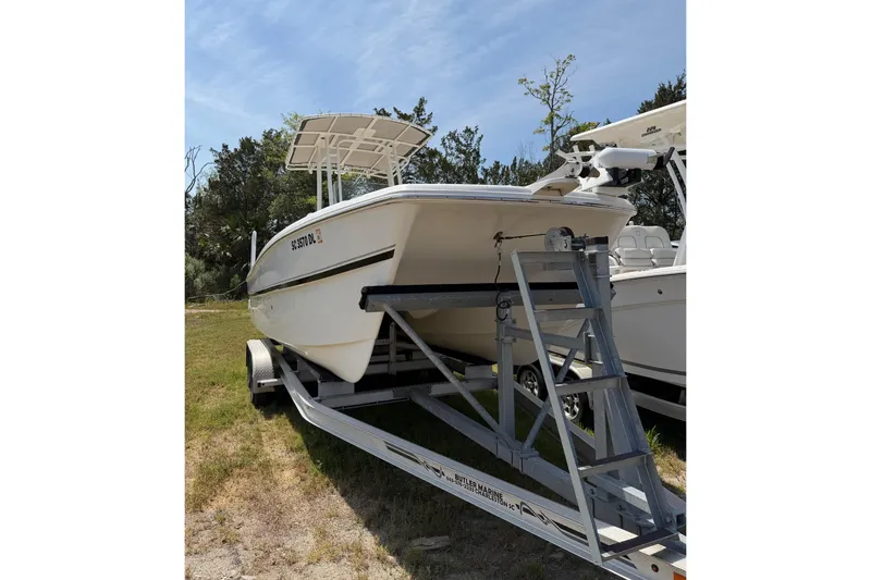 Slide: The Image of 2019 World Cat 230 CC boat on trailer, parked outdoors under clear sky. - 64
