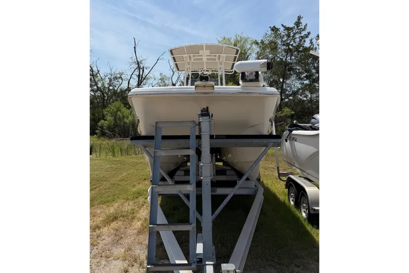 Slide: The Image of 2019 World Cat 230 CC boat on trailer, parked outdoors with trees in background. - 66