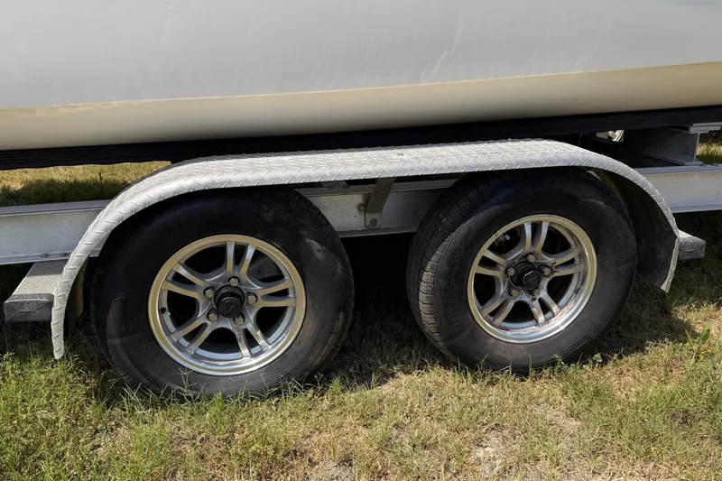 Slide: The Image of Trailer wheels of a 2019 World Cat 230 CC boat on grass. - 69