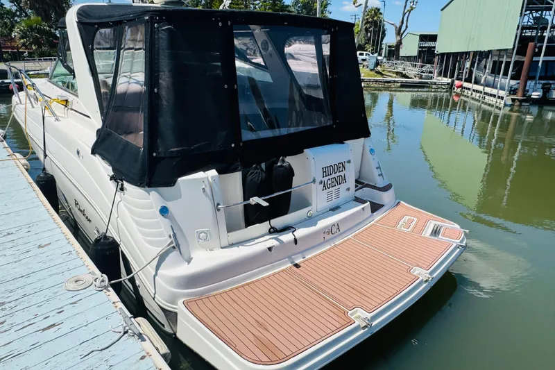 Slide: The Image of 2002 Rinker Fiesta Vee 342 boat docked with black canopy and wooden deck. - 10