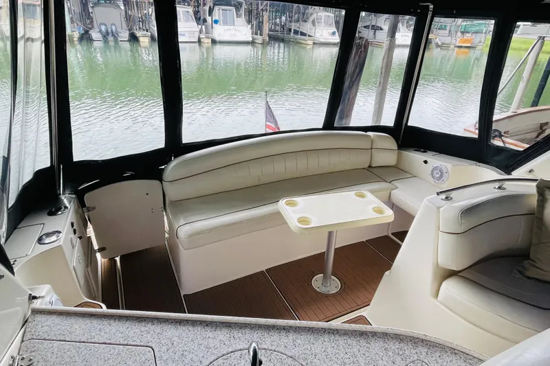 Slide: The Image of 2002 Rinker Fiesta Vee 342 boat interior with seating and table, docked by the water. - 15