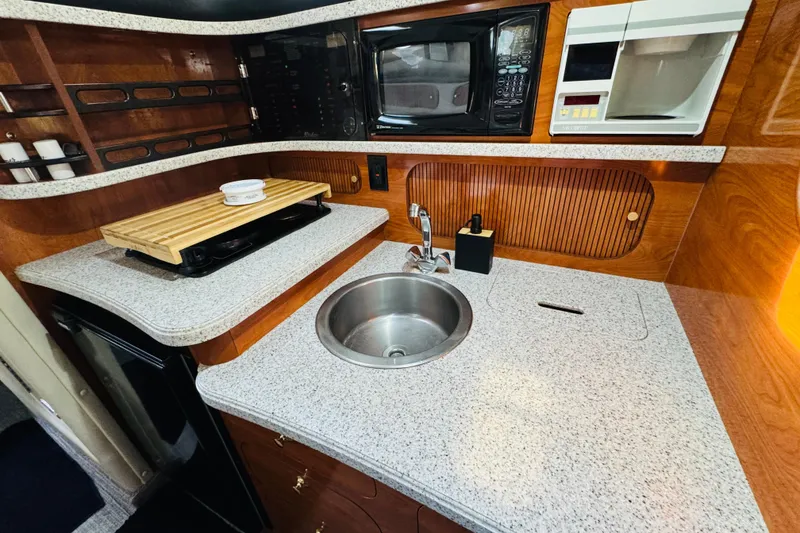 Slide: The Image of 2002 Rinker Fiesta Vee 342 boat kitchen with sink, microwave, and wooden cabinetry. - 43