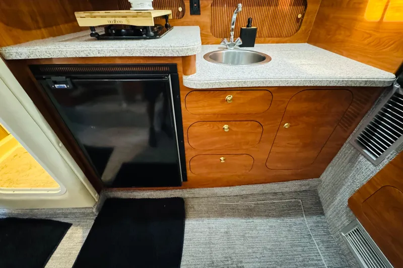 Slide: The Image of 2002 Rinker Fiesta Vee 342 cabin kitchen with sink, fridge, and wooden cabinetry. - 44