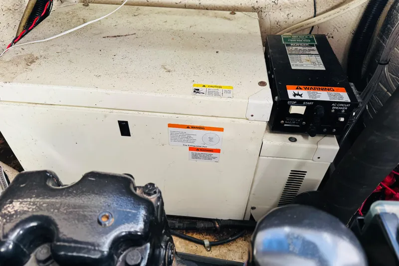Slide: The Image of Engine compartment of a 2002 Rinker Fiesta Vee 342 boat with generator and warning labels. - 54