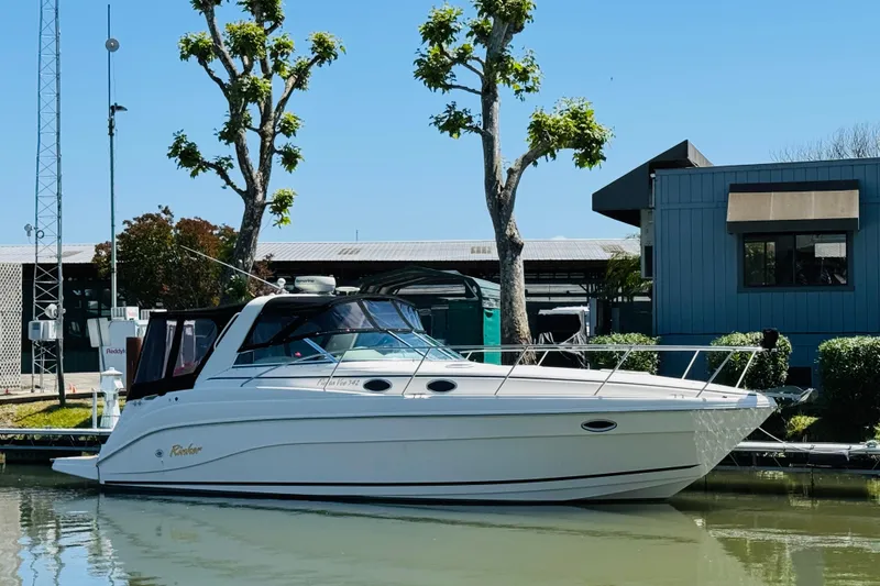 Slide: The Image of 2002 Rinker Fiesta Vee 342 boat docked near modern building and trees. - 6