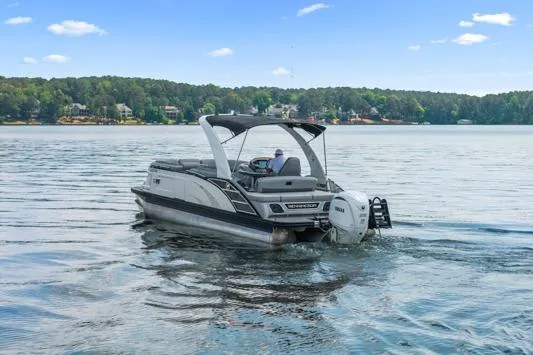The Image of 2023 Bennington QX 25 QXSBA pontoon boat cruising on a serene lake. - 1