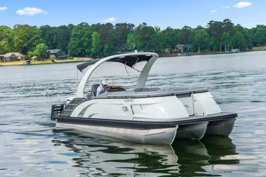 Slide: The Image of 2023 Bennington QX 25 QXSBA pontoon boat cruising on a scenic lake. - 3