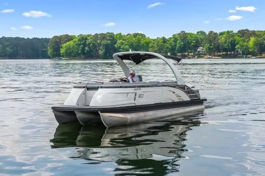 Slide: The Image of 2023 Bennington QX 25 QXSBA pontoon boat cruising on a serene lake. - 4