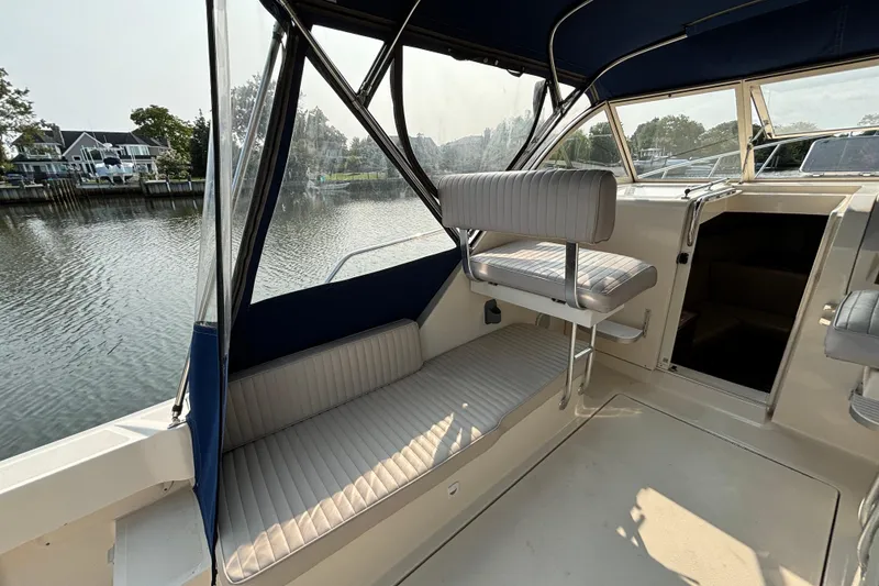 Slide: The Image of 2005 Mainship Pilot 30-II Sedan interior with seating, docked by a serene waterfront. - 13