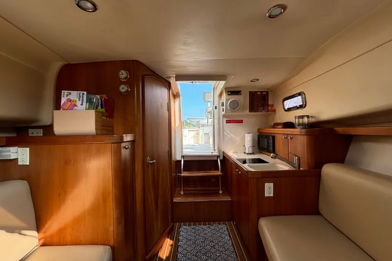 Slide: The Image of Interior of 2005 Mainship Pilot 30-II Sedan, featuring wood cabinetry and compact kitchen area. - 20