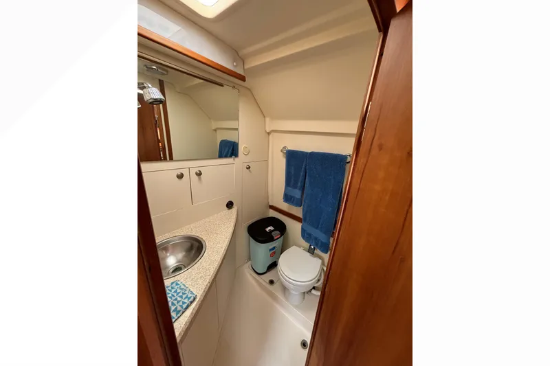 Slide: The Image of 2005 Mainship Pilot 30-II Sedan bathroom with sink, toilet, and blue towels. - 32