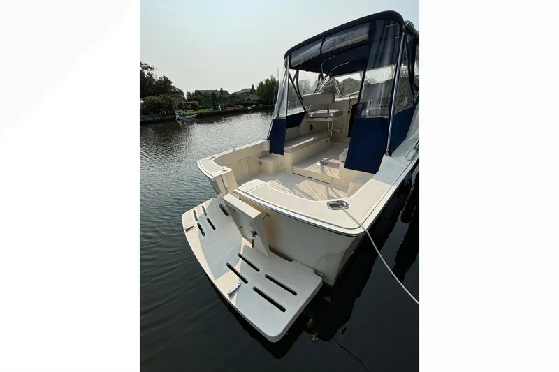 Slide: The Image of 2005 Mainship Pilot 30-II Sedan boat docked, featuring spacious deck and blue canopy. - 4
