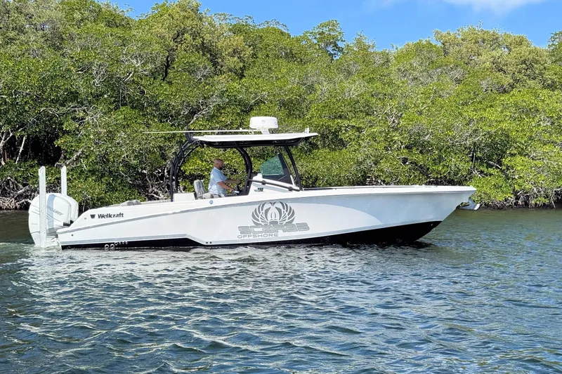 The Image of 2021 Wellcraft 302 Fisherman boat cruising on a calm river near lush greenery. - 1