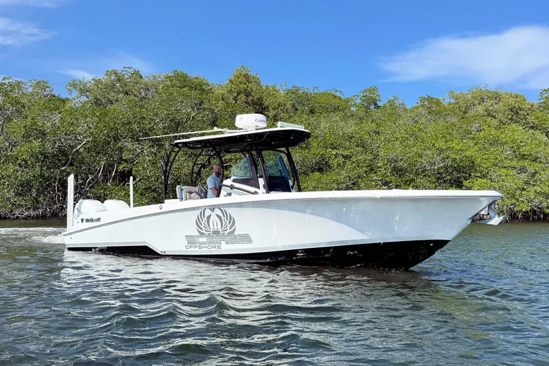 Slide: The Image of 2021 Wellcraft 302 Fisherman boat cruising on water near lush greenery. - 3